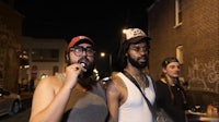 a group of men standing on a street at night