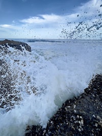 a wave crashing over rocks on a beach