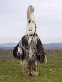 a man dressed in a traditional costume is standing in a field