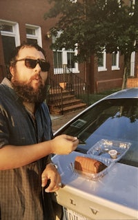 a man with a beard standing next to a car