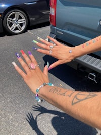 two people with tattoos on their hands in a parking lot