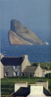 a ship is floating in the ocean near a house